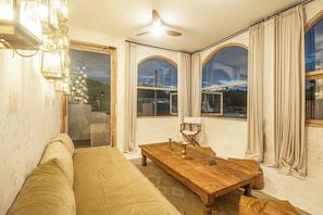 A room with a wooden table, a sofa, and a chandelier. - Stylish 3BR Villa Uluwatu Enclosed Living & AC (Pecatu)