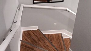 Un escalier avec des marches en bois et un miroir à cadre noir au-dessus.