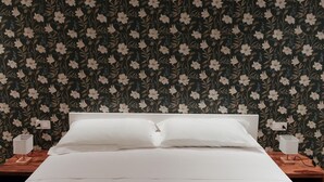 Un letto con lenzuola bianche, una testiera in legno e due comodini con lampade.