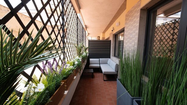 Un balcone con angolo salotto, piante in vaso e vista sulla strada.