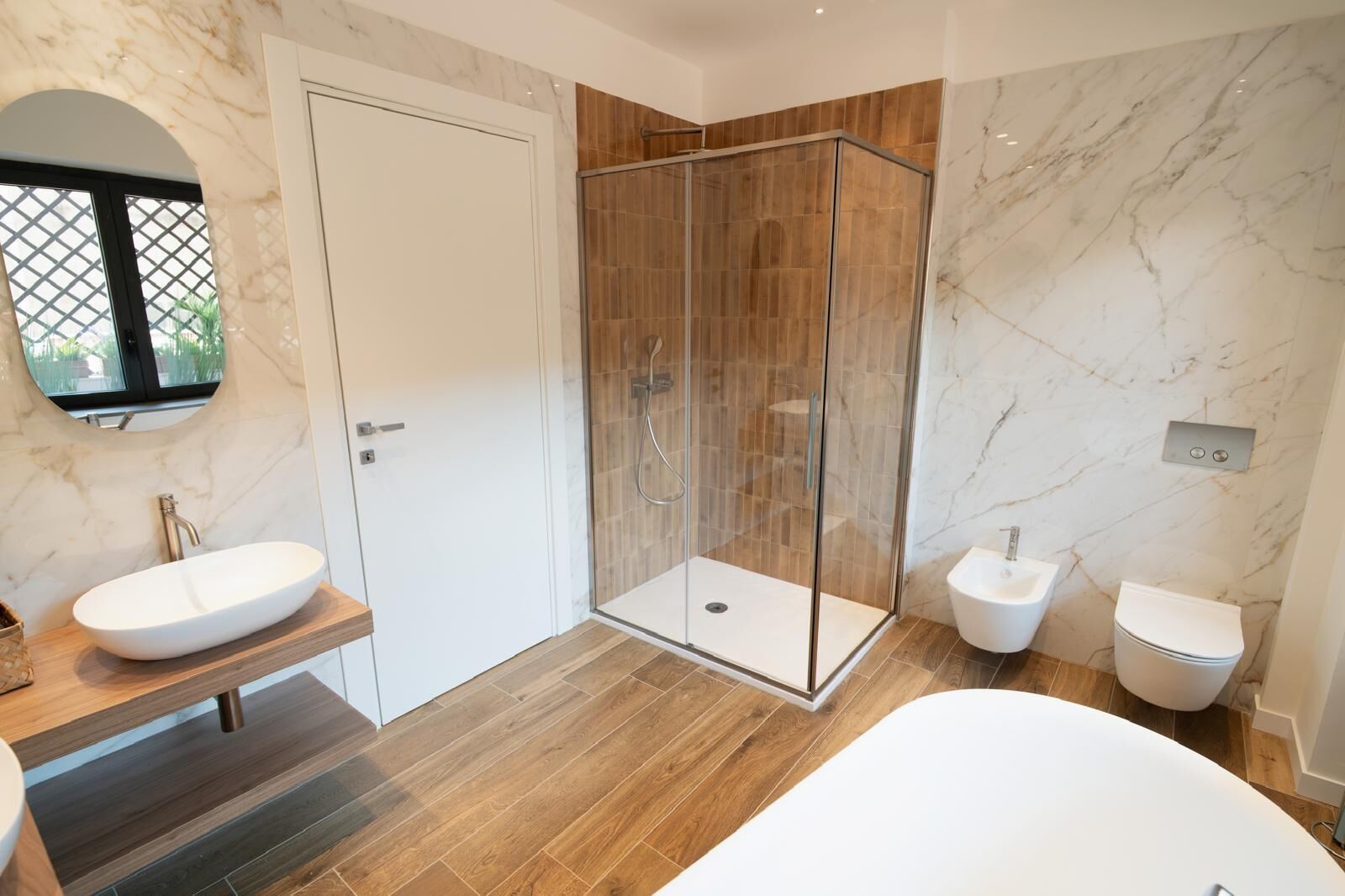 Ein modernes Badezimmer mit einer gläsernen Duschkabine, einer freistehenden Badewanne und einem Doppelwaschtisch.