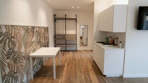 Una cucina moderna con mobili bianchi, un piano di lavoro in legno e un piano cottura integrato.