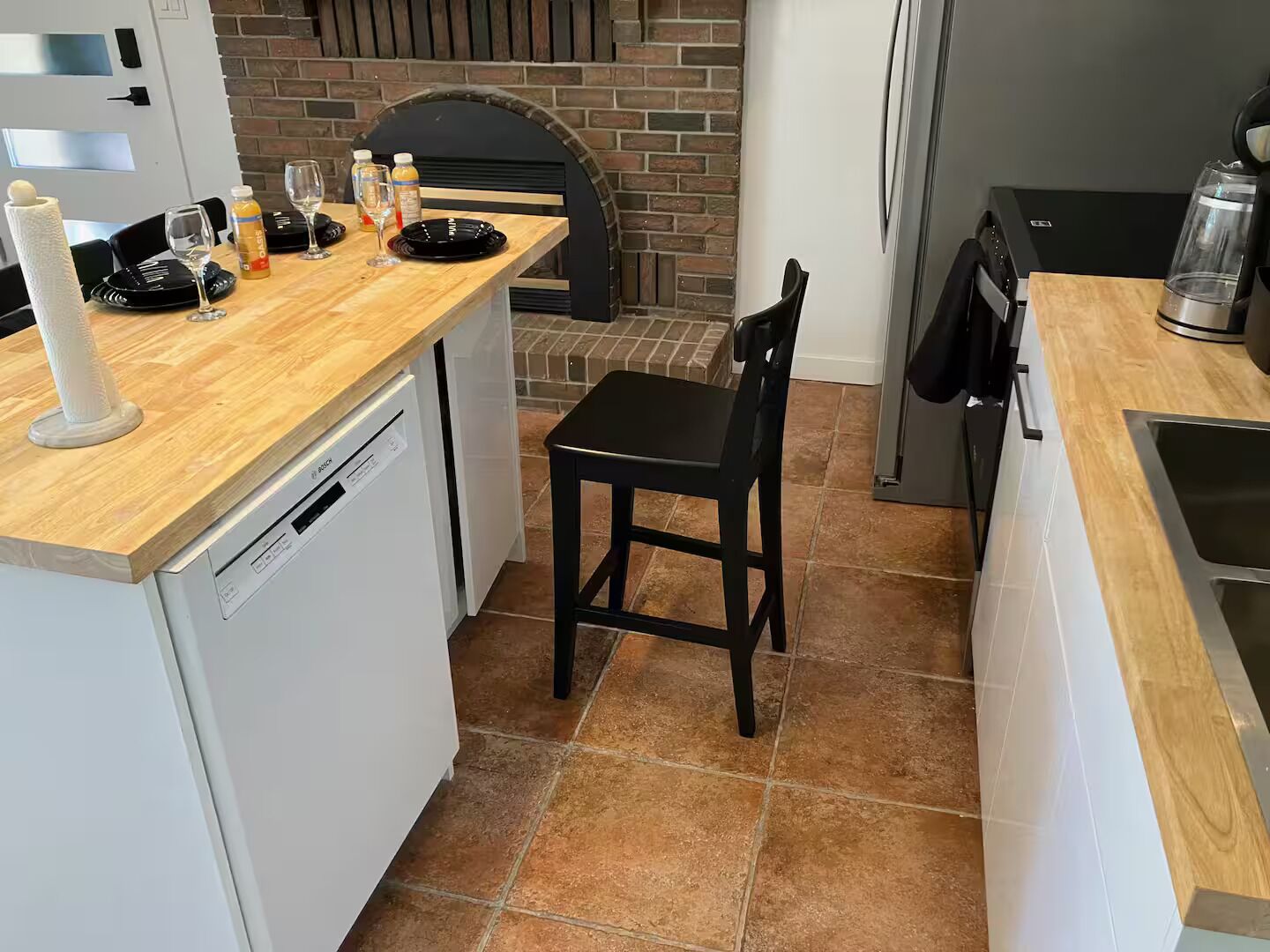 A compact kitchen with a dishwasher, a sink, and a wooden countertop.