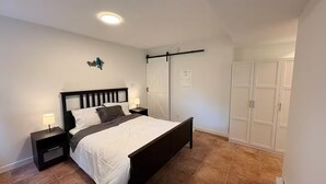 Ein Schlafzimmer mit einem Bett, Nachttischen, einem Kleiderschrank und einer Deckenleuchte.