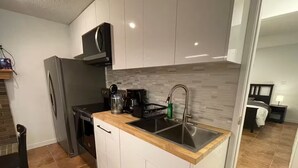 A compact kitchen with a built-in microwave, a coffee maker, and a sink.