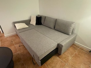 A grey sofa with a matching cover, a black chair, and a white cushion. - Modern Bright Lynn Valley Suite with Patio, Parking & Evergreen Surroundings (North Vancouver)