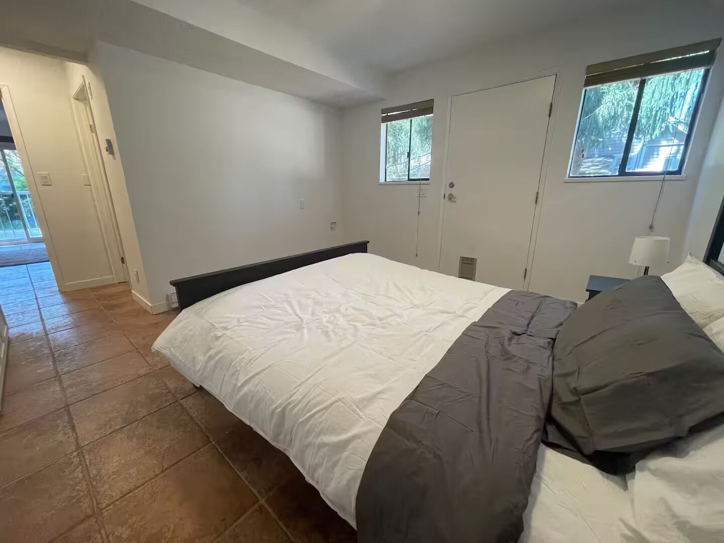 Une chambre à coucher avec un lit, une table de chevet, une fenêtre et une porte.