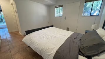 Une chambre à coucher avec un lit, une table de chevet, une fenêtre et une porte.