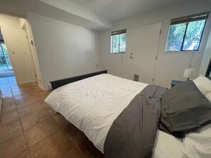 Une chambre à coucher avec un lit, une table de chevet, une fenêtre et une porte.