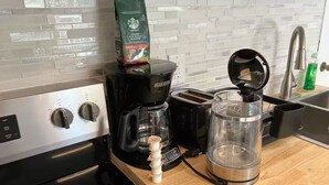Eine Küche mit einer Kaffeemaschine, einem Toaster und einem Wasserkocher auf der Arbeitsfläche.