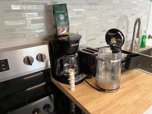 A kitchen with a coffee maker, a toaster, and a kettle on the counter.