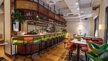A bar area with a long counter, multiple stools, and a seating area with tables and chairs.