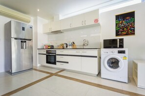 A modern kitchen with a stainless steel refrigerator, an oven, a microwave, and a washing machine. - 1 Bedroom Beach Villa Apartment (Koh Chang)
