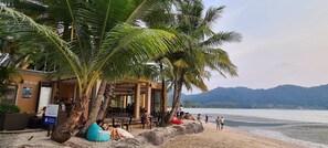 A beachside cafe with outdoor seating, palm trees, and a view of the sea. - 1 Bedroom Beach Villa Apartment (Koh Chang)
