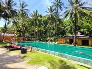 A swimming pool with lounge chairs and palm trees. - 1 Bedroom Beach Villa Apartment (Koh Chang)