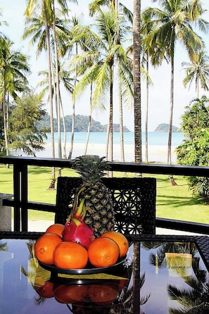 A tropical view with a table displaying fruits and a chair.