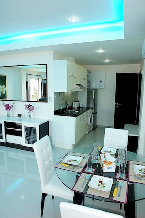 A modern kitchen with white cabinetry, a built-in oven, and a washing machine.