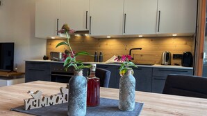 Ett modernt kök med träskåp, ett matbord med en bordsduk och två dekorativa vaser med blommor.