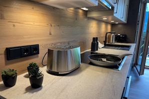 A modern kitchen with a wooden backsplash, stainless steel appliances, and a window providing natural light. - Panoramic view apartment Kaunergrat (Kaunerberg)