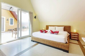 Ein Hotelzimmer mit Bett, Nachttisch, Lampe und Blick ins Freie.