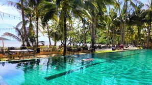 A clear pool with a view of the beach, surrounded by palm trees and lounge chairs. - Beach Villa 21D Blue Haven Bay Resort - 4 rooms (Ko Chang)