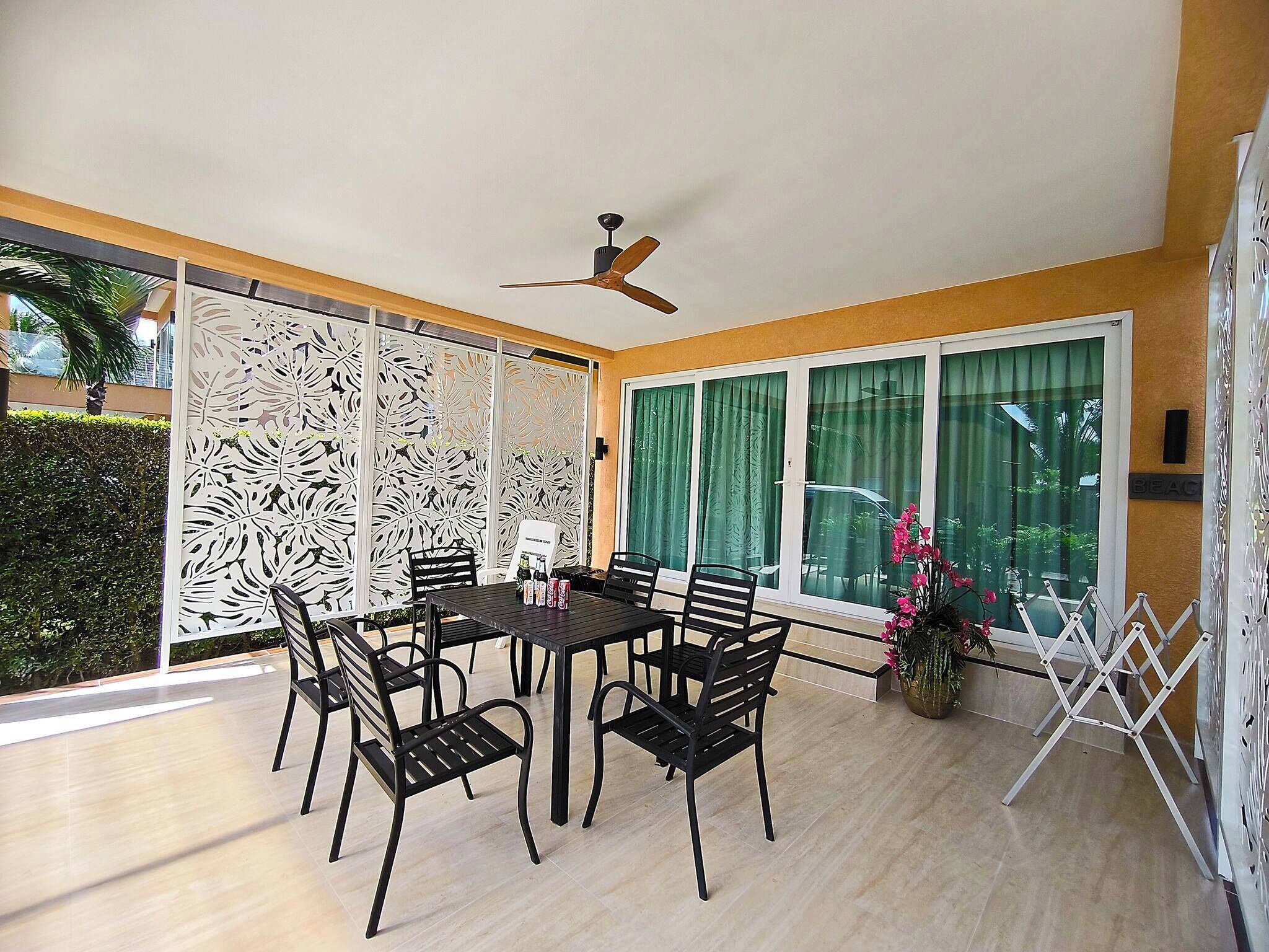 A dining area with a table and chairs, a ceiling fan, and large windows with curtains.
