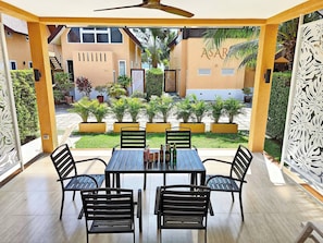An outdoor patio with a table and chairs, surrounded by potted plants and a view of buildings. - 1 Bedroom Villa with Beach View Koh Chang (Ko Chang)