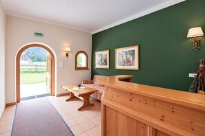 A reception area with a wooden bench, a table, a sofa, and two framed paintings on the wall. - Tyrolean Apartment with Terrace (Achenkirch)