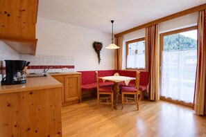 A cozy kitchen with wooden cabinets, a red bench, and a table with chairs. - Tyrolean Apartment with Terrace (Achenkirch)