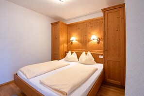 A double bed with a wooden headboard and two wall-mounted lamps. - Tyrolean Apartment with Terrace (Achenkirch)