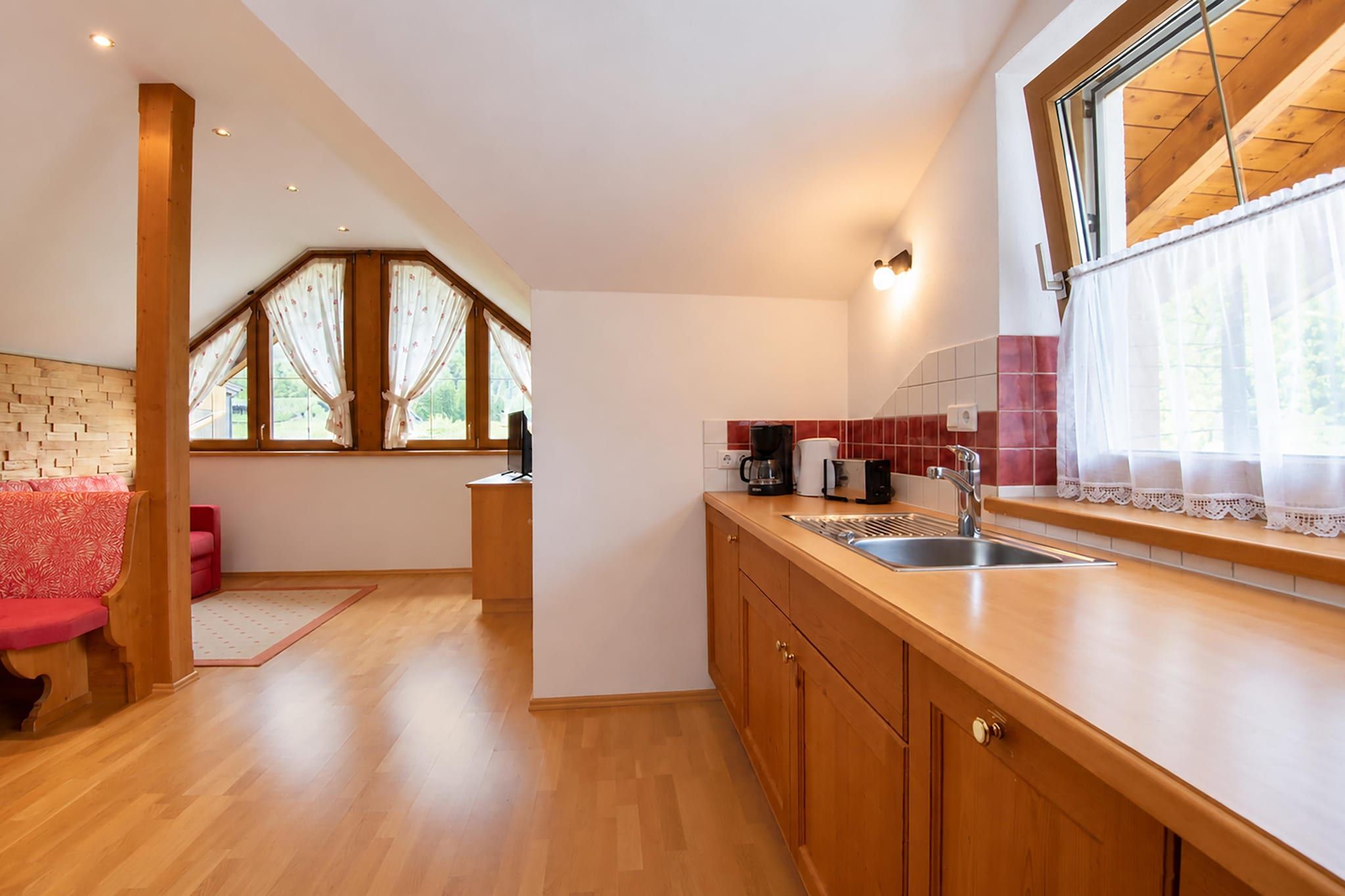 Une cuisine moderne avec des meubles en bois, un évier en acier inoxydable et une fenêtre agrémentée de rideaux.