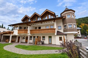 A multi-story building with a central courtyard, wooden balconies, and a stone pathway. - Holiday apartment in an Alpine setting (Achenkirch)