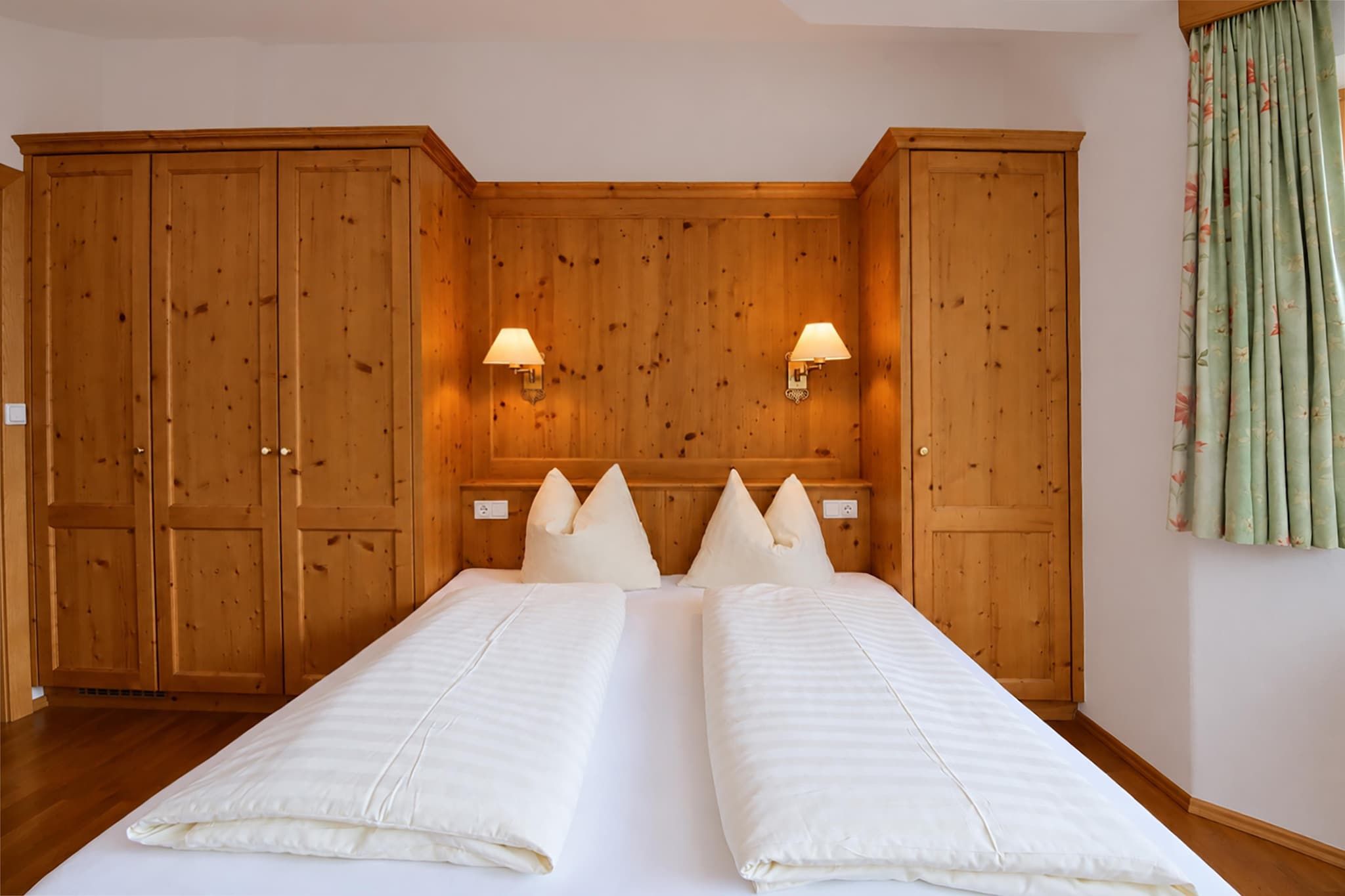 Una stanza con un letto matrimoniale, un'armadietto in legno e due lampade a parete.