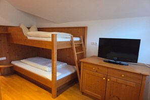 Une chambre avec un lit superposé et un téléviseur posé sur une commode en bois.