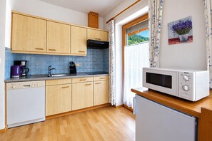 A kitchen with wooden cabinets, a sink, a stove, a microwave, and a refrigerator. - Modern holiday apartment near Lake Achensee (Achenkirch)