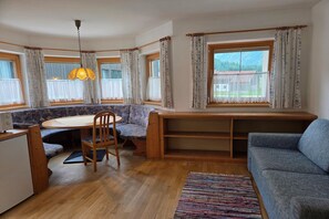 A cozy room with a wooden dining table, a blue sofa, and a bench with a view of the outdoors.