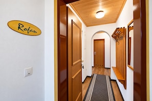 A hallway with wooden doors, a nameplate, and a bench. - Modern holiday apartment near Lake Achensee (Achenkirch)