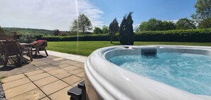 Ein Whirlpool in einem Hinterhof mit einer Terrassenanlage und Gartenmöbeln.
