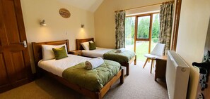 A room with two wooden beds, a desk, and a radiator. - Osborne Collection at The Victorian Barn Dorset – Sleeps 24, 2 Hot Tubs (Blandford Forum)