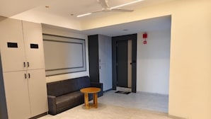 A hotel lobby with a sofa, a round wooden table, and a ceiling fan. - HOTEL HILL VIEW (Ahmedabad)