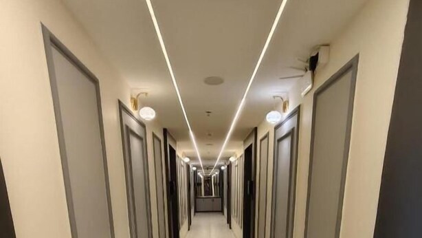 A hotel corridor with a herringbone floor pattern, doors on both sides, and a linear light fixture on the ceiling. - HOTEL HILL VIEW (Ahmedabad)