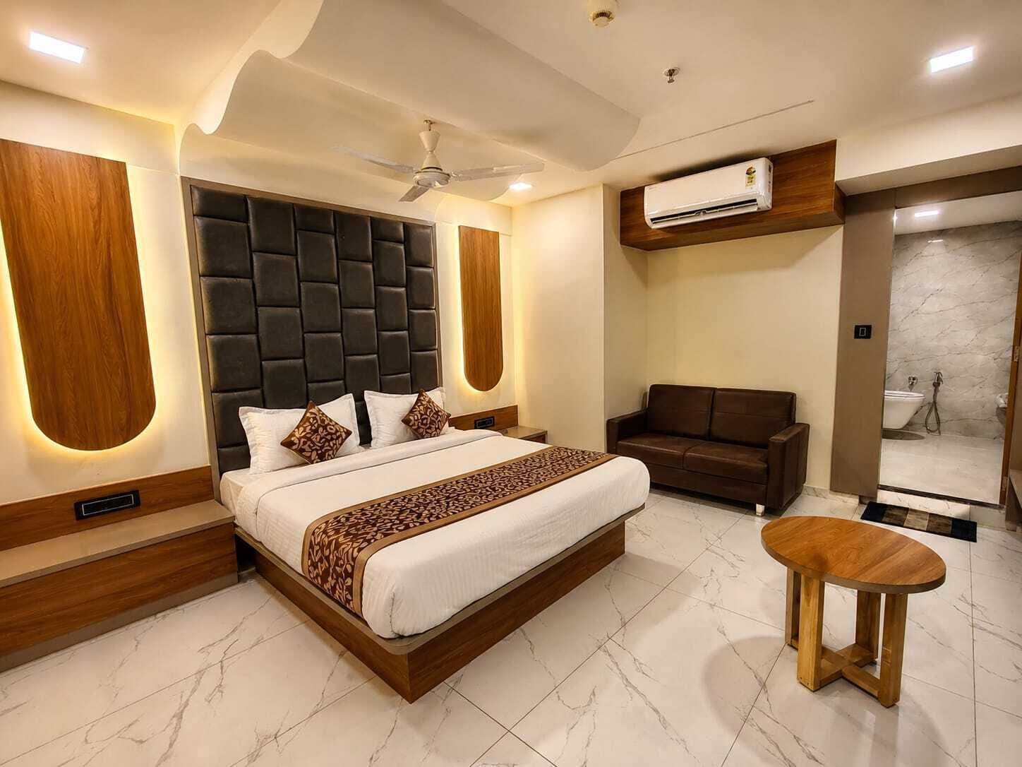 Un dormitorio moderno con una cama grande, un ventilador de techo, un equipo de aire acondicionado, un rincón de descanso y vistas al baño.