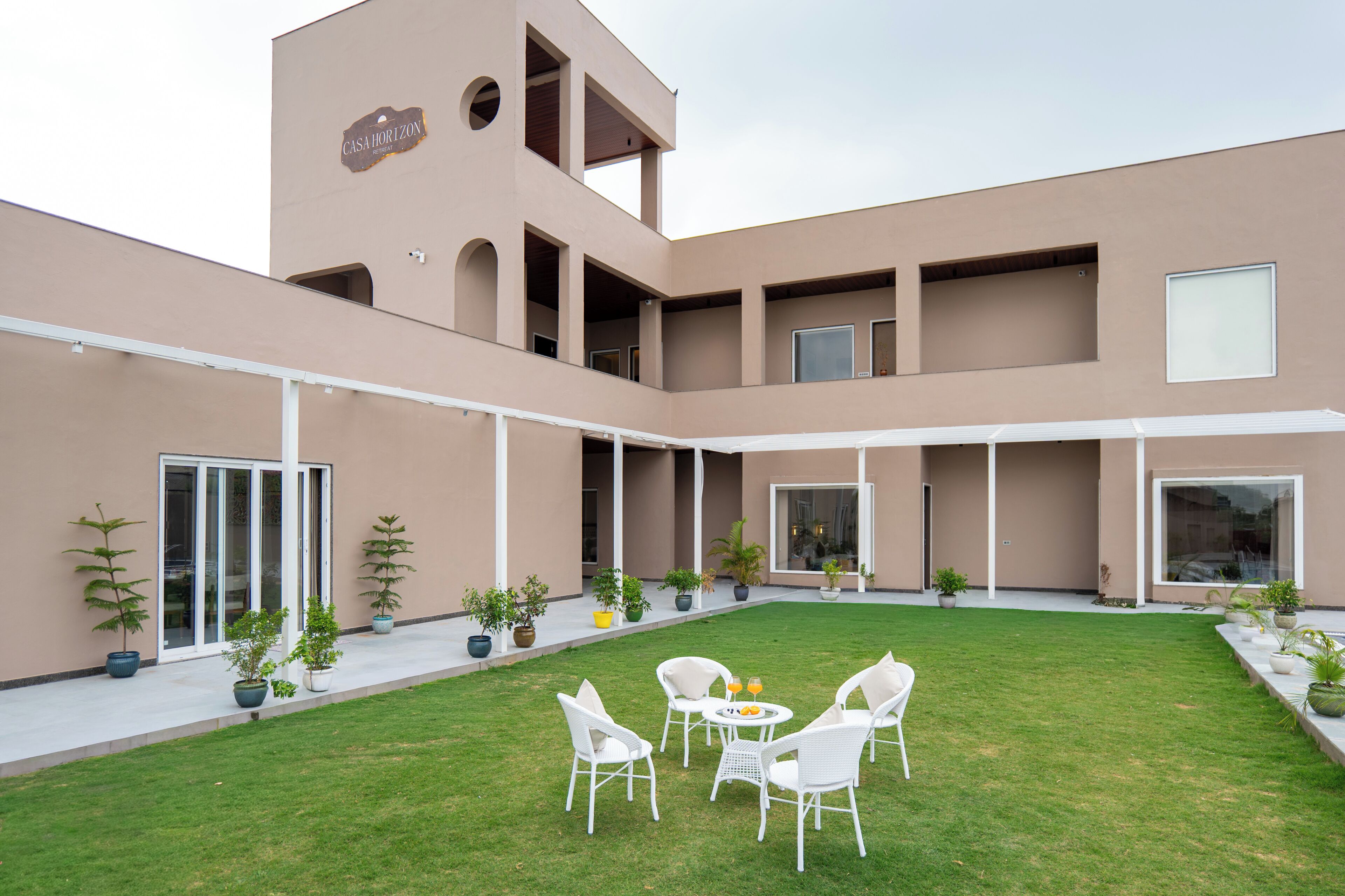 A modern building with a courtyard featuring outdoor seating and potted plants.