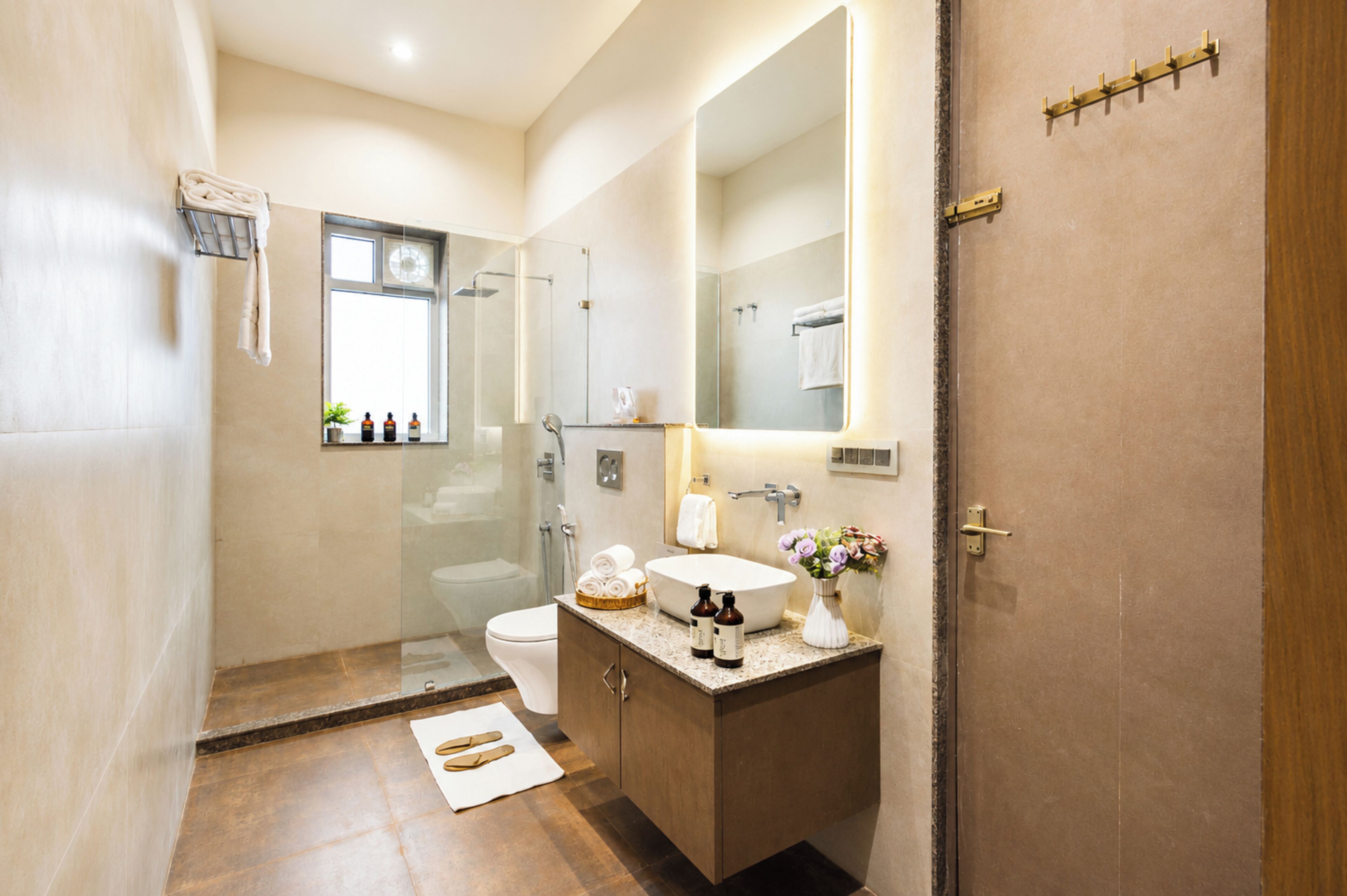 A modern bathroom with a glass-enclosed shower, a toilet, a sink with a mirror, and a wooden vanity.