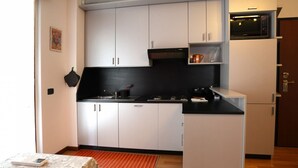 A compact kitchen with white cabinets, a black countertop, and a microwave. - GuestHost - Good morning, Monza! Cozy Apartment (Monza)