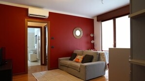 A living room with a sofa, a rug, and a red wall. - GuestHost - Good morning, Monza! Cozy Apartment (Monza)