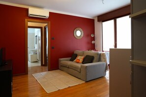 Uma sala de estar com um sofá, um tapete e uma parede vermelha.