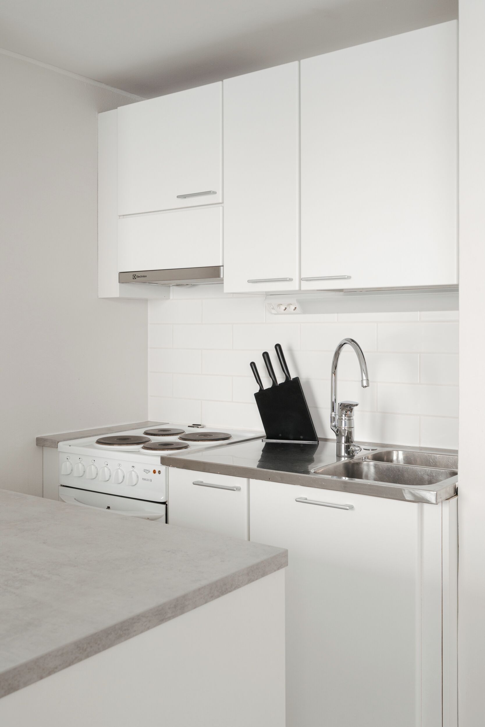 A modern kitchen with white cabinets, a stainless steel sink, and a gas stove.