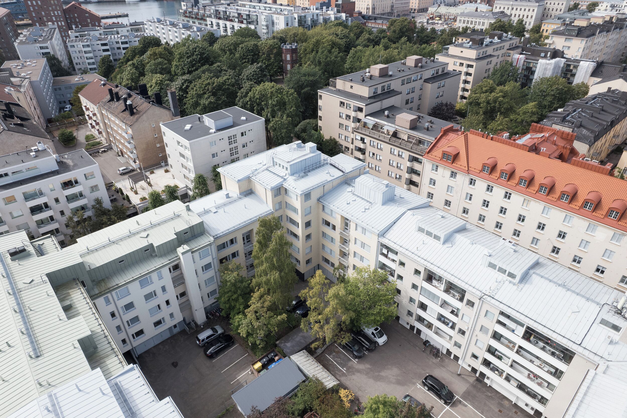 Un edificio residencial de gran altura con varios balcones, un estacionamiento y zonas verdes circundantes.