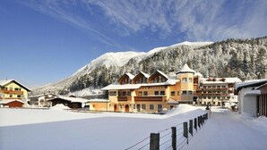 Une station de montagne enneigée, avec des bâtiments de style chalet, un ciel dégagé et une piste de ski au premier plan.